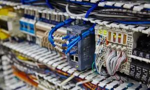 Złącze ark. z niebieskimi kablami sieciowymi i modułami Siemens. Widać też wiele przewodów i wskaźników LED.