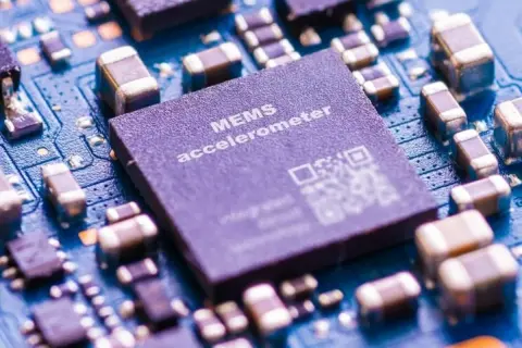 Zbliżenie na płytkę drukowaną z widocznym układem MEMS accelerometer, kluczowym elementem w telefonie do pomiaru ruchu.