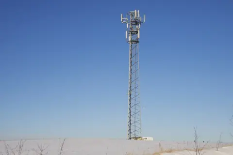 Wieża telekomunikacyjna na tle błękitnego nieba. Wokół śnieg. To może być część infrastruktury TDD, co to jest?