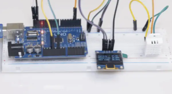 Projekt am2302: Arduino Uno z czujnikiem temperatury i wilgotności DHT22, wyświetlaczem OLED i płytką stykową.