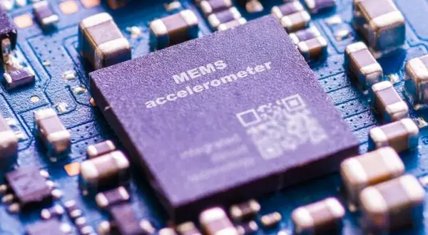 Zbliżenie na płytkę drukowaną z widocznym układem MEMS accelerometer, kluczowym elementem w telefonie do pomiaru ruchu.