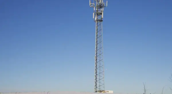 Wieża telekomunikacyjna na tle błękitnego nieba. Wokół śnieg. To może być część infrastruktury TDD, co to jest?