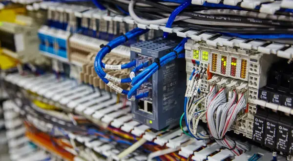 Złącze ark. z niebieskimi kablami sieciowymi i modułami Siemens. Widać też wiele przewodów i wskaźników LED.