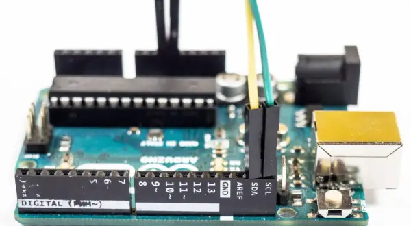 Płytka Arduino z podłączonymi przewodami. Programista tworzy pętlę `while` do sterowania urządzeniami.