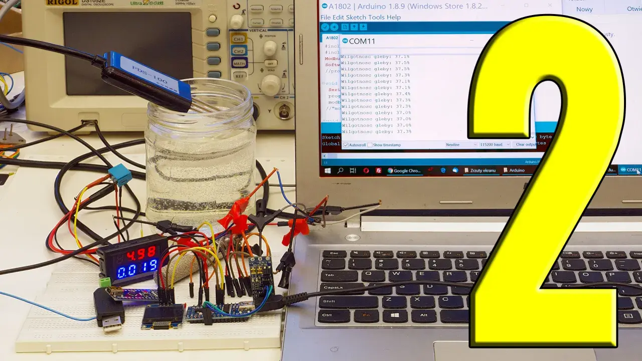 Pomiar napięcia Arduino z użyciem sondy w wodzie. Na ekranie komputera widać kod i wyniki pomiarów wilgotności gleby.
