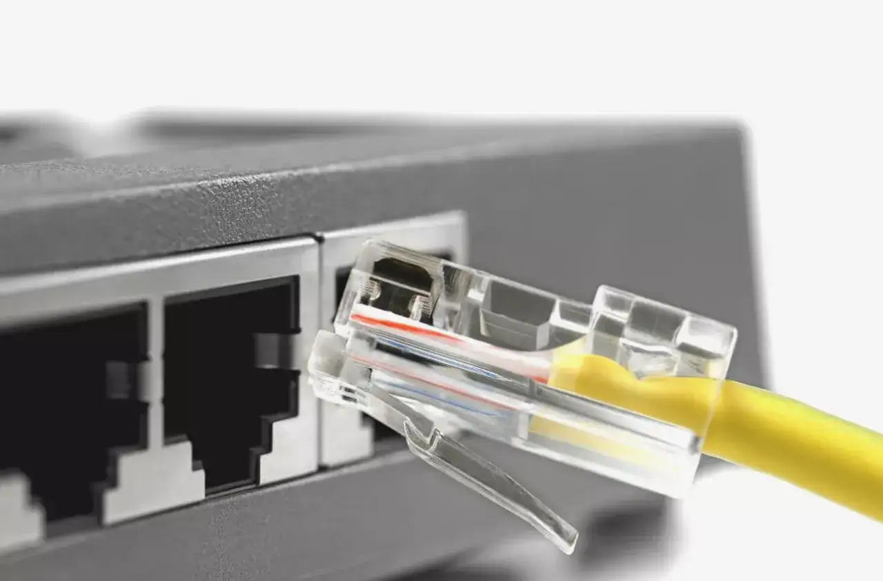 Żółty kabel sieciowy z przezroczystą wtyczką RJ45 gotowy do połączenia ethernet z portem routera.