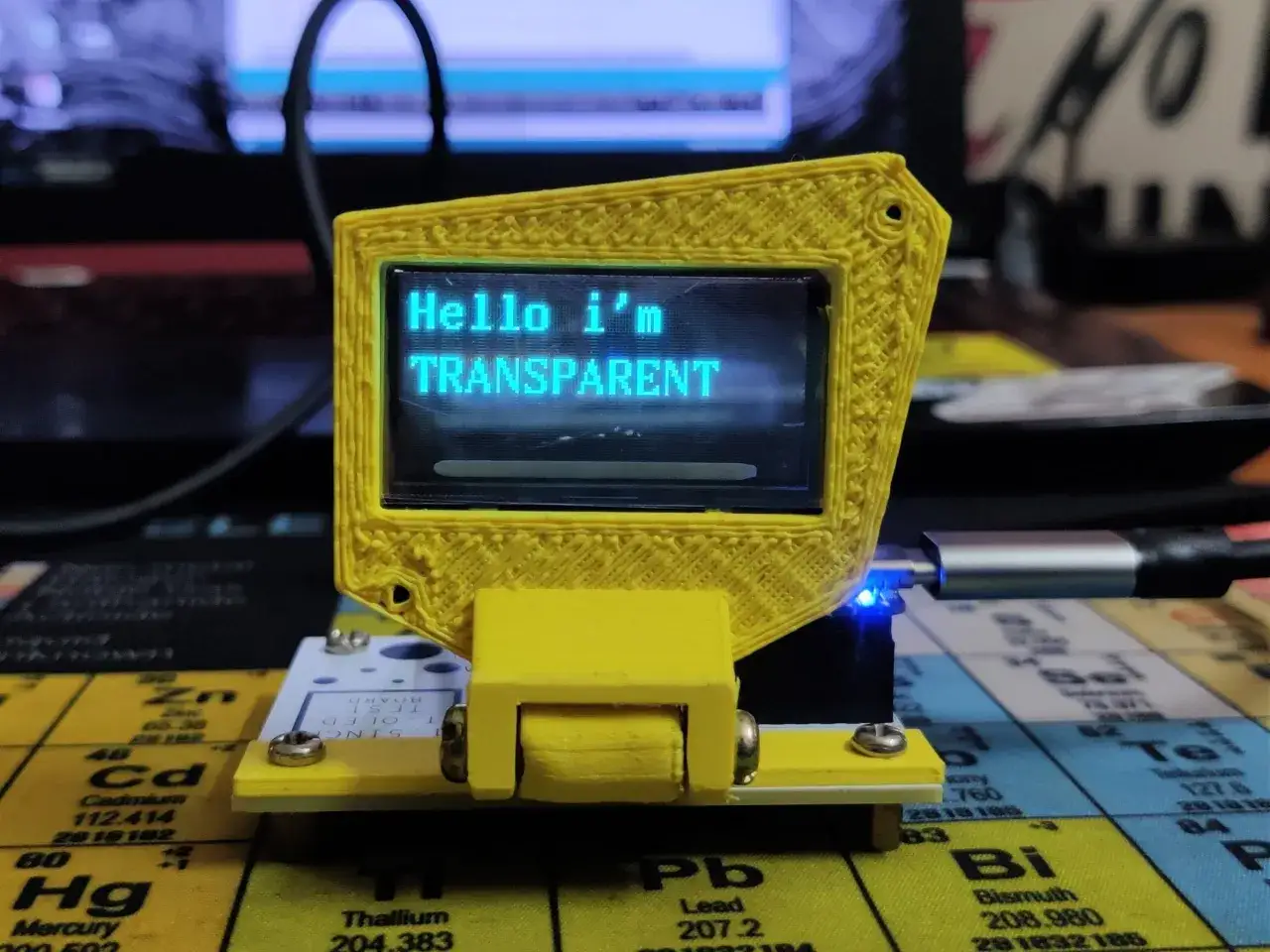 Żółta obudowa z wyświetlaczem transparent oled, na którym widnieje napis