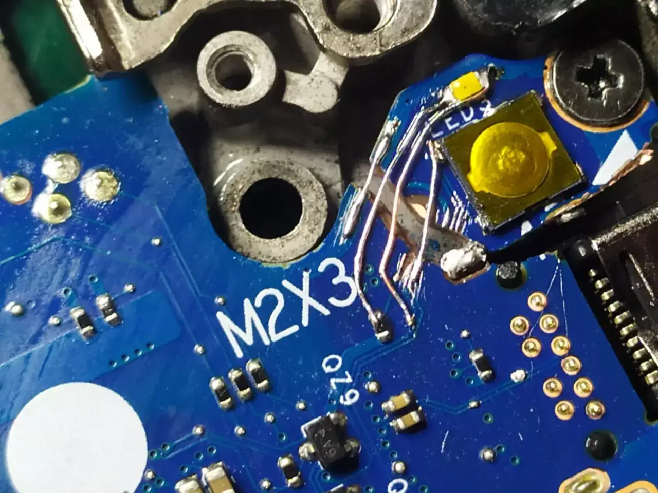 Naprawa ścieżki na płytce M2X3 za pomocą drucików. Widoczne elementy elektroniczne i lutowanie.