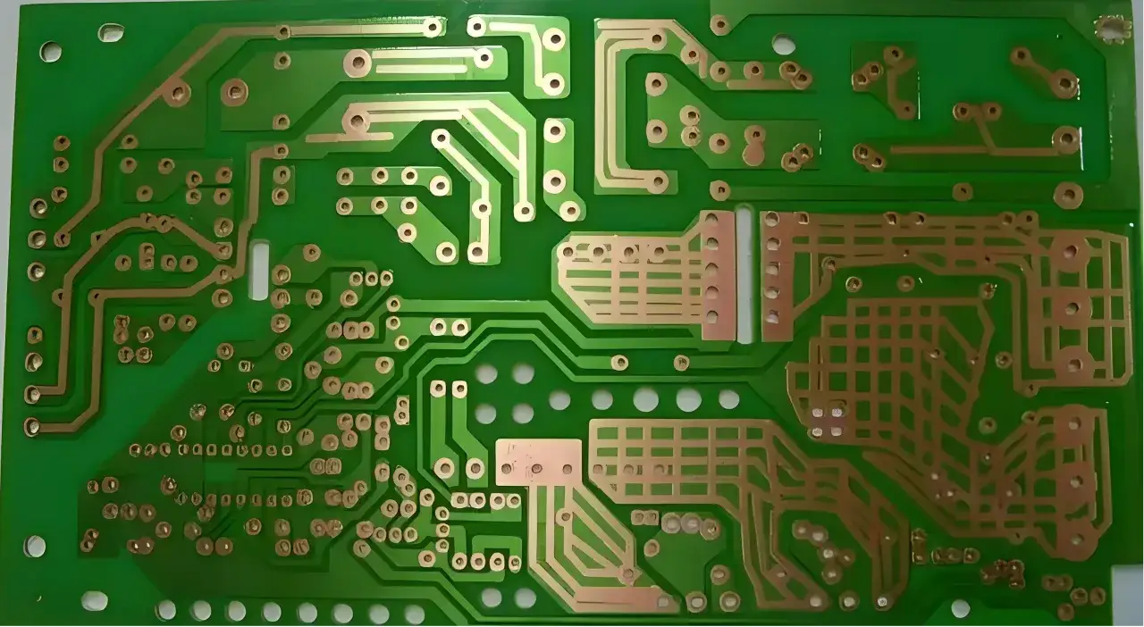 Zielona płytka drukowana z miedzianymi ścieżkami i otworami. To jest laminat, podstawa elektroniki.