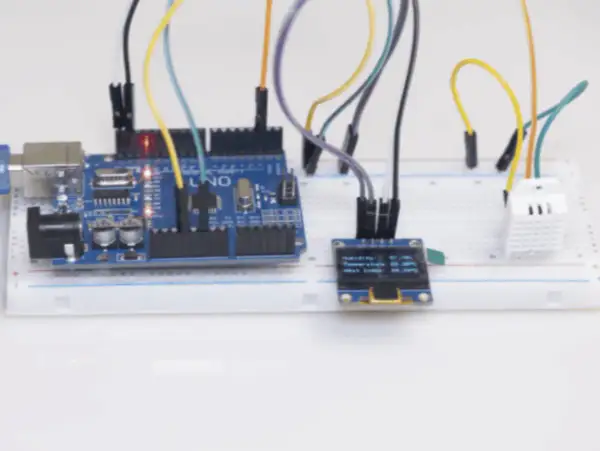 Projekt am2302: Arduino Uno z czujnikiem temperatury i wilgotności DHT22, wyświetlaczem OLED i płytką stykową.