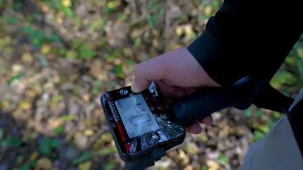 Ręka trzymająca cyfrowy wyświetlacz wykrywacza metali. To urządzenie, czyli magnetometr, pomaga znaleźć ukryte przedmioty.