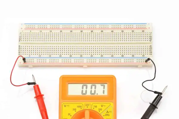 Płytka stykowa jak działa: połączenia elektryczne na płytce stykowej i multimetr pokazujący pomiar.